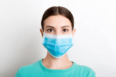 Beyaz arka planda tıbbi maske takan genç bir kadının portresi. Sağlığınızı koruyun. Coronavirus konsepti.