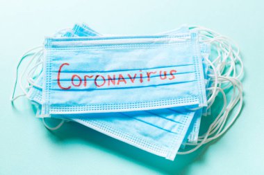 Koronavirüs kelimesinden yapılmış salgın geçmişi mavi arka plandaki koruyucu tıbbi maske yığınıyla ilgili. Dünya karantina kavramı.