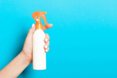 Mavi arkaplandaki kozmetik spreyini tutan kadın eli tasarımınız için boş bir alan..