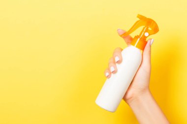 Kozmetik spreyini kapat kadın eline, sarı arkaplanda fotokopi alanı ile..