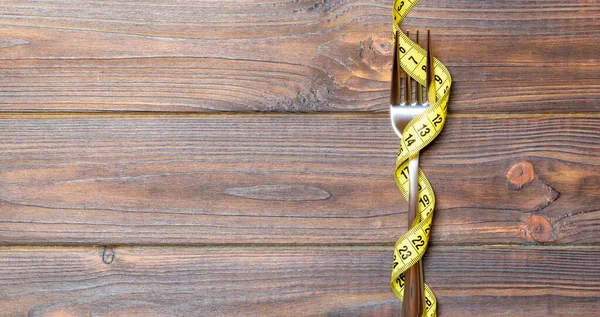 木製の背景にテープメジャーでラップフォークのトップビュー 健康的な食事とダイエットの概念 — ストック写真