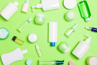 Plastik vücut bakımı şişesi grubu düz tasarım için yeşil arka plan boş alan kozmetik ürünleri ile kompozisyon yatıyordu. Beyaz Kozmetik Konteynerler, kopya alanı ile üst görünüm seti.