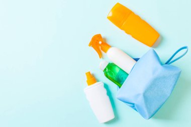 Kadın kozmetik çanta güneş kremi sprey, sunsreen, güneş kremi ve vücut losyonu ve kopya alanı ile mavi arka plan üzerinde spf krem dolu üst görünümü. Tam üstünde. Parlak yaz konsepti.
