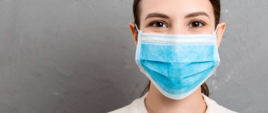 Gri çimento arka planda tıbbi maske takan genç bir kadının portresi. İnsan sonunda sağlıklı olduğu için mutlu. Sağlığınızı koruyun. Coronavirus konsepti.
