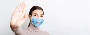 Coronavirus metniyle tıbbi maskeli bir kadının portresi ve beyaz arka planda dur hareketi gösteriyor. Coronavirus konsepti. Solunum koruması.