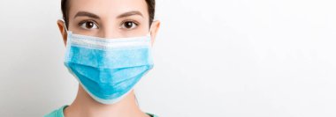 Beyaz arka planda tıbbi maske takan genç bir kadının portresi. Sağlığınızı koruyun. Coronavirus konsepti.