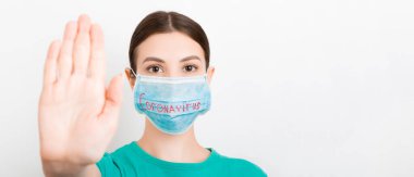 Coronavirus metniyle tıbbi maskeli bir kadının portresi ve beyaz arka planda dur hareketi gösteriyor. Coronavirus konsepti. Solunum koruması.