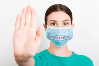 Coronavirus metniyle tıbbi maskeli bir kadının portresi ve beyaz arka planda dur hareketi gösteriyor. Coronavirus konsepti. Solunum koruması.