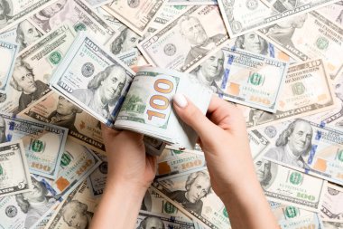 Kadın ellerinin farklı dolar arkaplanındaki paraları sayması. Borç konsepti. Yatırım kavramı.