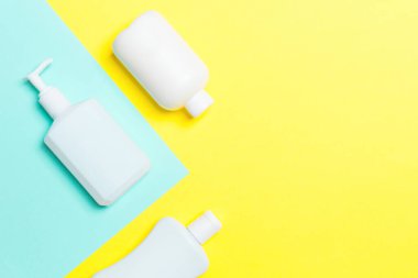 Beyaz Kozmetik kaplar seti sarı ve mavi arka planda izole edilmiş, fotokopi alanı olan üst manzara. Senin için bir grup plastik kaplar ve boş bir yer tasarladın..