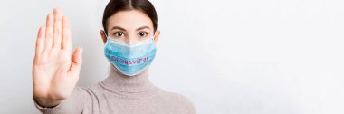 Coronavirus metniyle tıbbi maskeli bir kadının portresi ve beyaz arka planda dur hareketi gösteriyor. Coronavirus konsepti. Solunum koruması.
