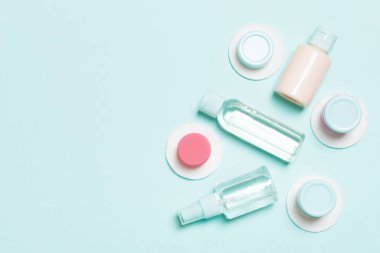 Yüz bakımı araçlarının en üst görünümü: şişeler ve kavanozlar dolusu tonik, su, krema, mavi arka planda pamuk pedleri. Fikirleriniz için boş midye içeren vücut bakım konsepti.