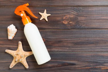 kopya alanı ile koyu ahşap masa üzerinde deniz kabukları ile güneş koruma krem şişeleri. Seyahat sağlık aksesuarları üst görünüm.