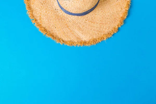 yellow retro straw hat top view with copy space. summer concept on blue background.