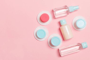 Pembe arka plan üzerinde seyahat boyutu kozmetik şişe seti. Krem kavanoz düz yatıyordu. Vücut bakımı tarzı kavramının en iyi görünümü.