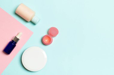 Pembe ve mavi arka planda kozmetik ürünleri için farklı kozmetik şişeleri ve konteynırların üst görüntüsü. Kopya alanı olan düz konum.