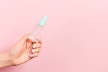 Kozmetik şişesini kadın eliyle kapatın. Pembe arka planda fotokopi alanı ile birlikte..