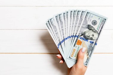 Tahta arka planda 100 dolarlık banknotların kadın eli hayranıyım. Yatırım kavramı .