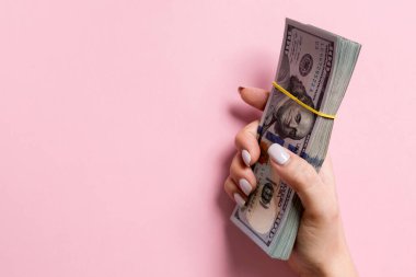 Renkli arka planda kadın elinde yüz dolarlık banknotlar demeti. Kopyalama alanı ile finans ve iş kavramı.