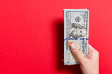 Kadın el renkli arka plan üzerinde para bir demet tutan. 100 dolarlık banknotların en iyi görünümü. Tasarım için boş alan ile Maaş kavramı.