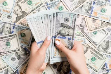 Kadın ellerinin farklı dolar arkaplanındaki paraları sayması. Borç konsepti. Yatırım kavramı.