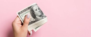 Renkli arka planda kadın elinde yüz dolarlık banknotlar bir paket. Kopya alanı ile maaş kavramı.