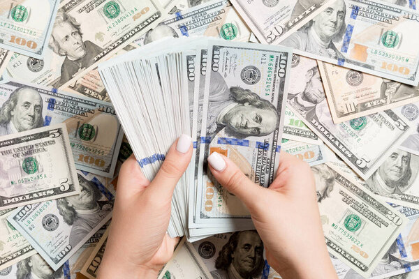 Вид сверху женских рук, считающих деньги на разном долларовом фоне. Концепция долга. Концепция инвестиций
.