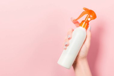 Kadının elinde pembe arka planda fotokopi alanı olan bir kozmetik ürünü tutarken yakın plan..