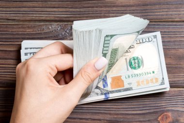 Para sayan kadın ellerinin en iyi görünümü. Renkli arka planda 100 dolarlık banknotlar. İş kavramı.