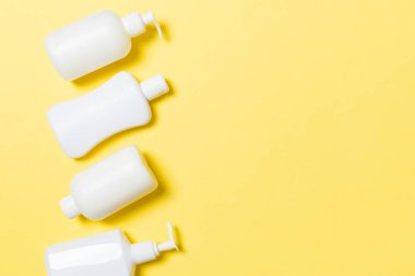Sarı arka planda izole beyaz Kozmetik Konteynerler seti, kopya alanı ile üst görünüm. Size tasarım için boş alan ile plastik vücut bakımı şişe kapları grubu.