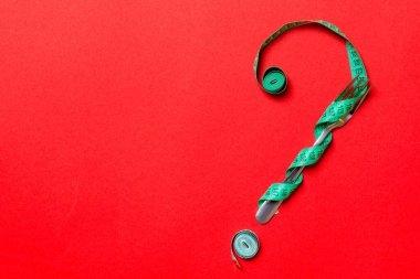 Kırmızı arkaplanda çatal ve mezuranın üst görünümü soru işareti şeklinde. Aşırı yeme kavramı ve kopyalama alanı.