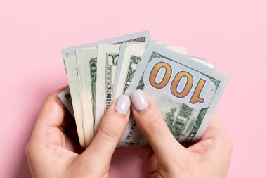 Renkli arka planda bir deste para tutan bir kadının üst görüntüsü. Çeşitli dolarlar. İş konsepti. Hayırseverlik ve bahşiş kavramı.