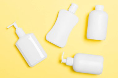 Sarı arka planda izole beyaz Kozmetik Konteynerler seti, kopya alanı ile üst görünüm. Size tasarım için boş alan ile plastik vücut bakımı şişe kapları grubu.