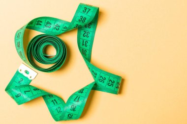 Ölçüm bandının üst görünümü kopyalama alanı olan bir spiral içine küçültülmüş. Turuncu arka planda aksesuar ya da sağlıklı beslenme kavramı.