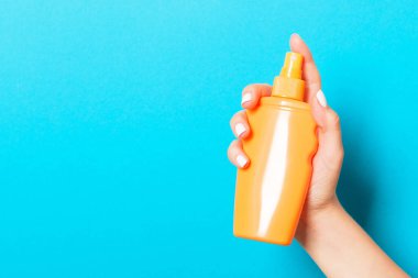 Mavi arka planda bir kozmetik ürünü spreyi tutan bir kadın eli. Tasarımınız için boş bir alan..