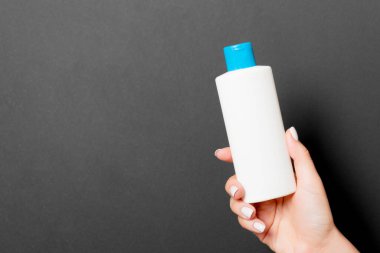 Kozmetik şişesini kadın eliyle kapatın. Siyah arkaplanda fotokopi alanı olsun..