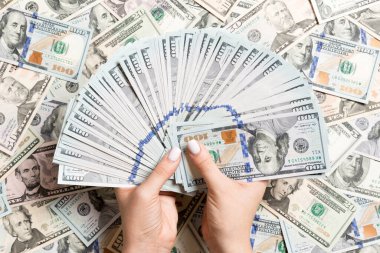Kadın ellerinin farklı dolar arkaplanındaki paraları sayması. Borç konsepti. Yatırım kavramı.