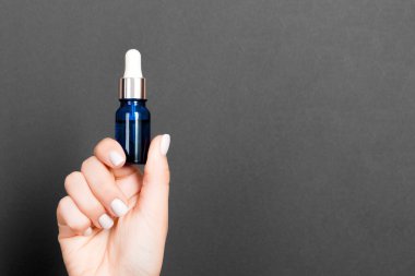 Elinde fotokopi alanı olan bir kozmetik şişesi tutan bir kadın eli..