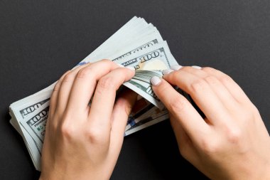 Renkli arka planda yüz dolarlık banknotlar sayan bir iş kadınının ellerinin en iyi görünümü. Başarı ve zenginlik kavramı.