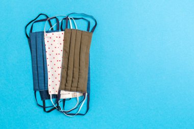 Mavi arka planda yeniden kullanılabilir ev yapımı tekstil maskelerinin üst görüntüsü. Fotokopi alanı ile solunum koruma kavramı. DIY kavramı.