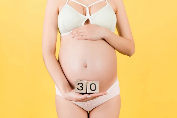 在怀孕的几个星期里 穿着五颜六色的内裤抱着立方体的孕妇的亲密接触 黄底怀孕30周 复制空间 — 图库照片