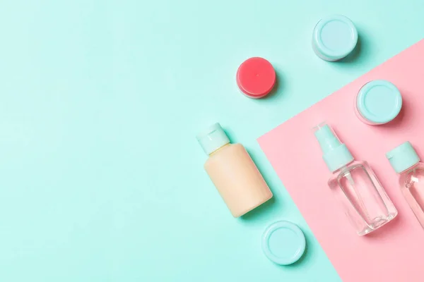 Top view of cosmetic containers, sprays, jars and bottles on pink background. Close-up view with empty space for your design.