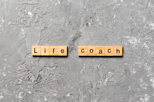 Life coach word written on wood block. Life coach text on cement table for your desing, concept.