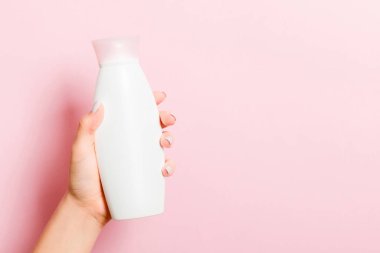 Kadın eli kozmetik şişesi ile pembe arkaplan ve tasarımınız için kopyalama alanı.