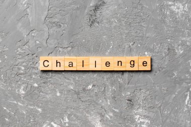 Ahşap blokta yazan CHALLENGE kelimesi. Çimento masasındaki CHALLENGE metin desing, konsept.
