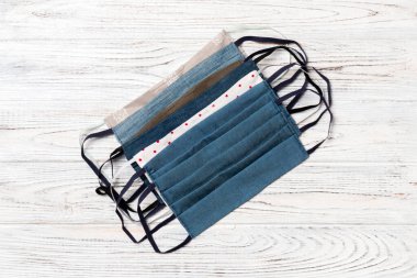 Ahşap arka planda yeniden kullanılabilir ev yapımı tekstil maskelerinin üst görüntüsü. Fotokopi alanı ile solunum koruma kavramı. DIY kavramı.