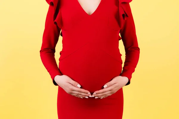 Imagen Recortada Las Manos Mujer Embarazada Abrazando Abdomen Fondo Amarillo — Foto de Stock