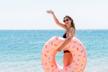 Çekici bir kadının uzun boylu portresi donut şişirilebilir yüzük tutuyor ve deniz dibinde elini sallıyor. Mutlu yazlar..