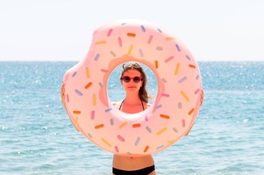 Güzel bir kadın plajda plajda plastik donut yüzüğüyle oynuyor..