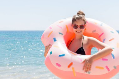 Donutun içindeki genç kadının portresi deniz arka planında şişirilebilir halka..